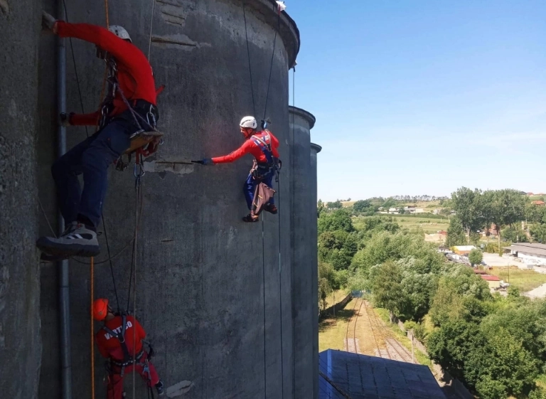 osoba zapięta w uprząż siedząca na desce